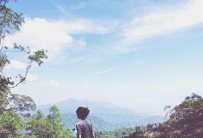 Rear view of woman on mountain against sky