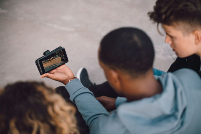 High angle view of male and female friends watching movie on smart phone