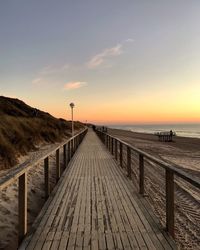 Pier over sea against sky during sunset