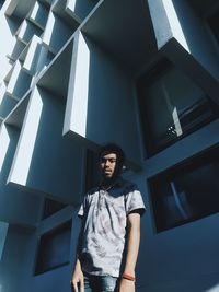 Low angle view of young man standing against building