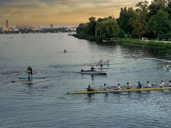 People on boats in lake against sky