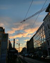 Cars on road in city against sky at sunset