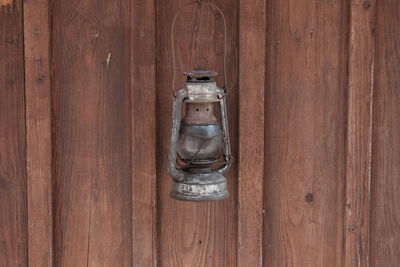 Old lantern hanging against wooden wall