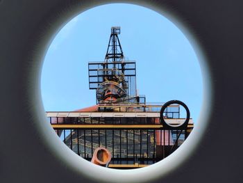 Low angle view of crane against clear sky seen through hole