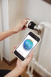 Woman using thermostat and app on phone