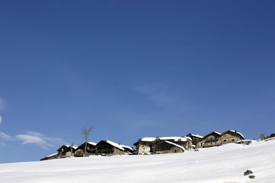 Houses on snowcapped landscape against sky