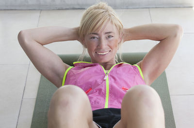 Portrait of smiling muscular woman doing sit-ups in gym