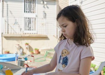 Young girl coloring pictures on a sunny day in the backyard