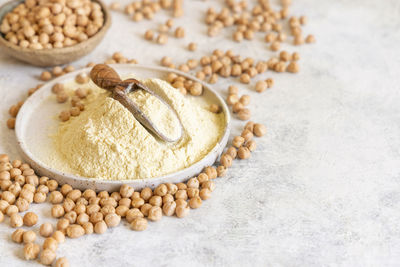 Plate of raw chickpea flour and beans on white table top view