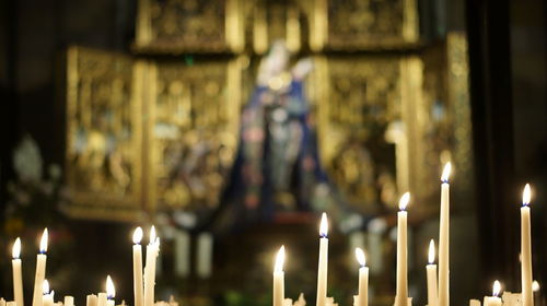 Lit candles in temple against building