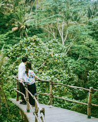 Rear view of couple standing at observation point in forest
