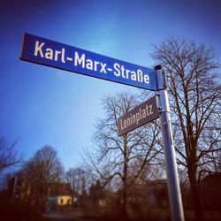 Low angle view of road sign against clear blue sky