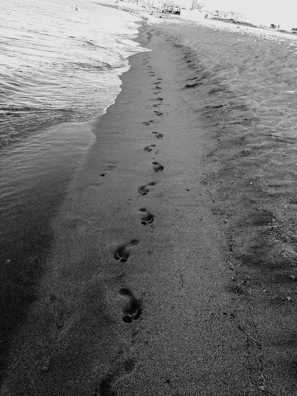 HIGH ANGLE VIEW OF FOOTPRINTS ON WET SHORE