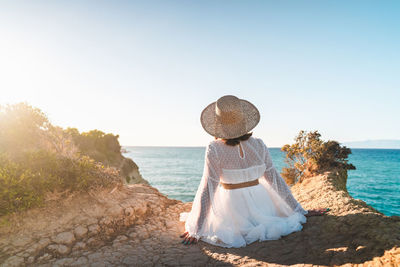 Rear view of woman on beach against clear sky