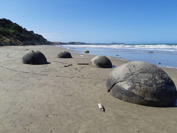 Rocks on beach against clear blue sky