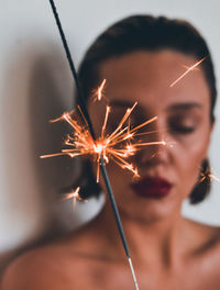 Close-up of woman with lit sparkler at home