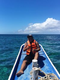 Man sitting in sea against sky