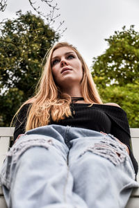 Close-up of young woman sitting against trees