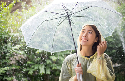 Portrait of a smiling young woman holding wet umbrella during monsoon