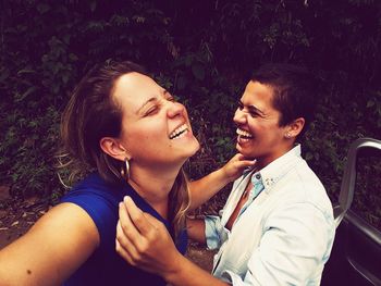 Two women laughing against plants