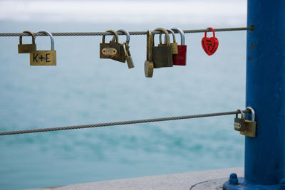 Close-up of padlocks hanging on railing against sea