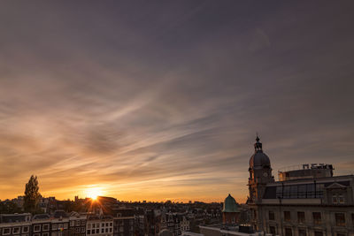 Buildings in city against sky during sunset
