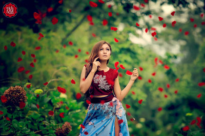 Full length of woman standing on red flowering plants