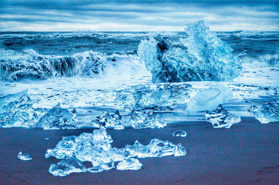 Water splashing on frozen sea against sky