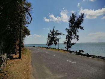 Scenic view of road by sea against sky