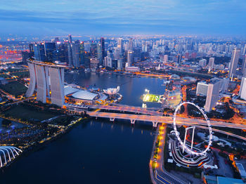 High angle view of illuminated city by river against sky