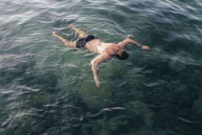 High angle view of shirtless man swimming in sea