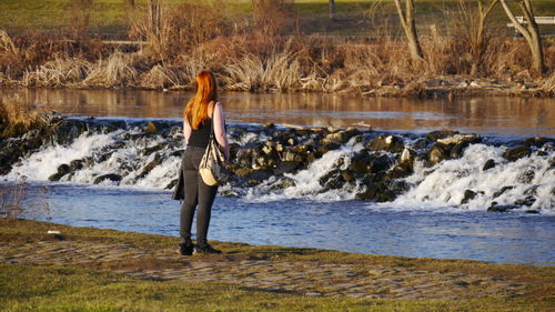 Woman standing on lakeshore at forest