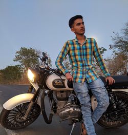 Young man riding motorcycle against sky