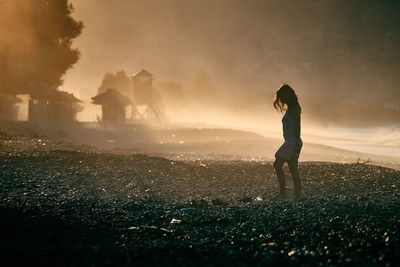 Silhouette of woman against cloudy sky