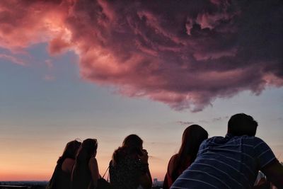 Silhouette people photographing sea against sky during sunset