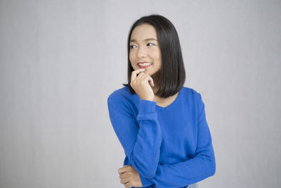 Portrait of smiling young woman against white background