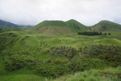 Scenic view of green landscape and mountains against sky