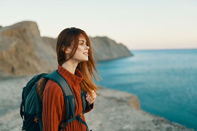 Young woman looking at sea against sky