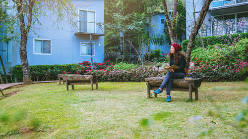 Woman sitting on bench against building