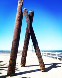 Cross on beach against clear blue sky