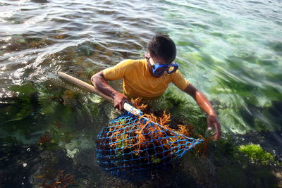 Man holding fishing net with coral in sea