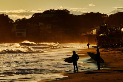 People on beach against sky during sunset