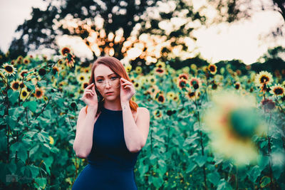 Portrait of young woman standing against plants
