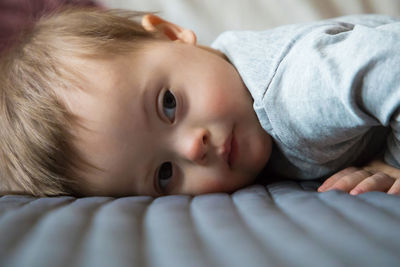 Close-up portrait of cute baby lying on bed at home