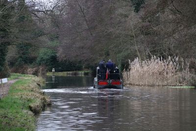 Rear view of people in river against trees in forest