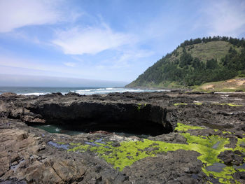 Scenic view of sea by mountain against sky