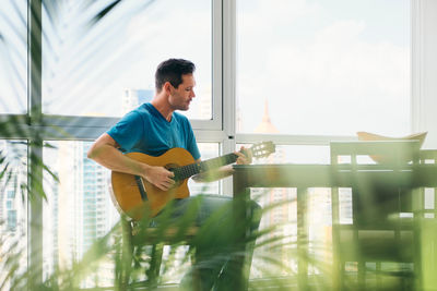 Man playing guitar in glass window