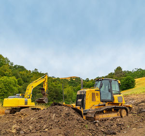 View of yellow bulldozer and excavator on plot of land. heavy equipment clears area. 