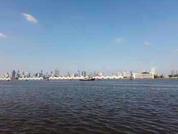 Sea by buildings in city against sky