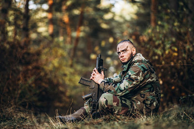 Midsection of man holding camera in forest